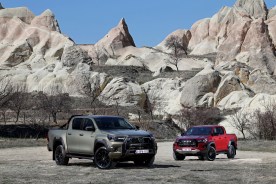 Dos Toyota Hilux 2025 sobre fondo rocoso. Una en color gris y otra en color vino